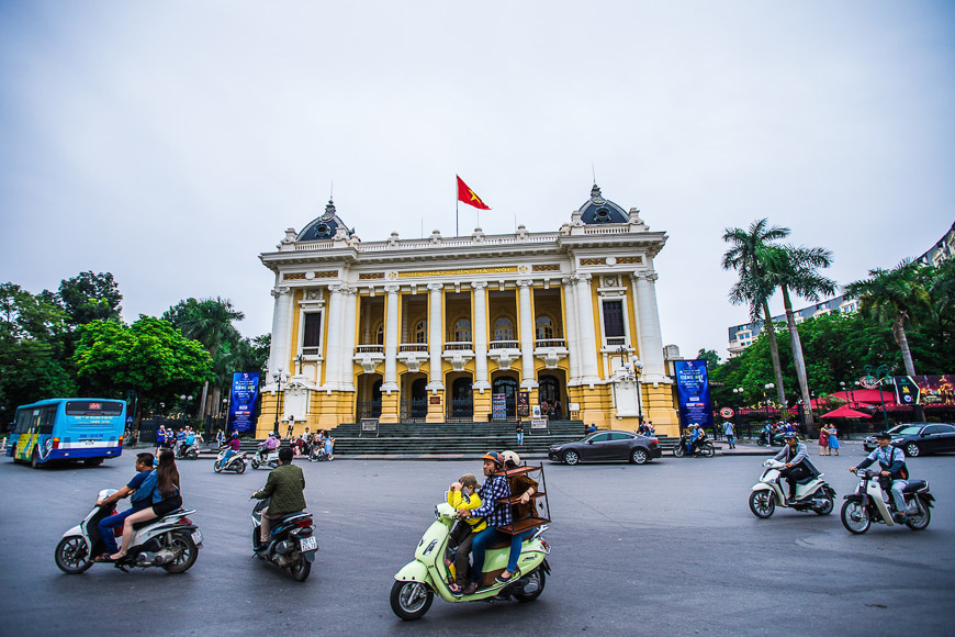 A group of people riding scooters in front of a building

Description automatically generated